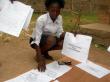 Une jeune femme fixe les listes Ã©lectorales sur des panneaux dans un bureau de vote de Bangui le 21 janvier 2011 (©  - Patrick Faure)